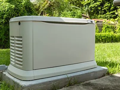 A beige home standby generator sits on a concrete pad
