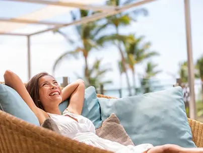 A joyful woman relaxes on a patio sofa with blue cushions