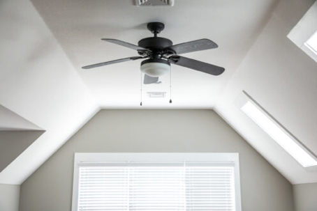 A properly installed black ceiling fan with a light fixture is centered